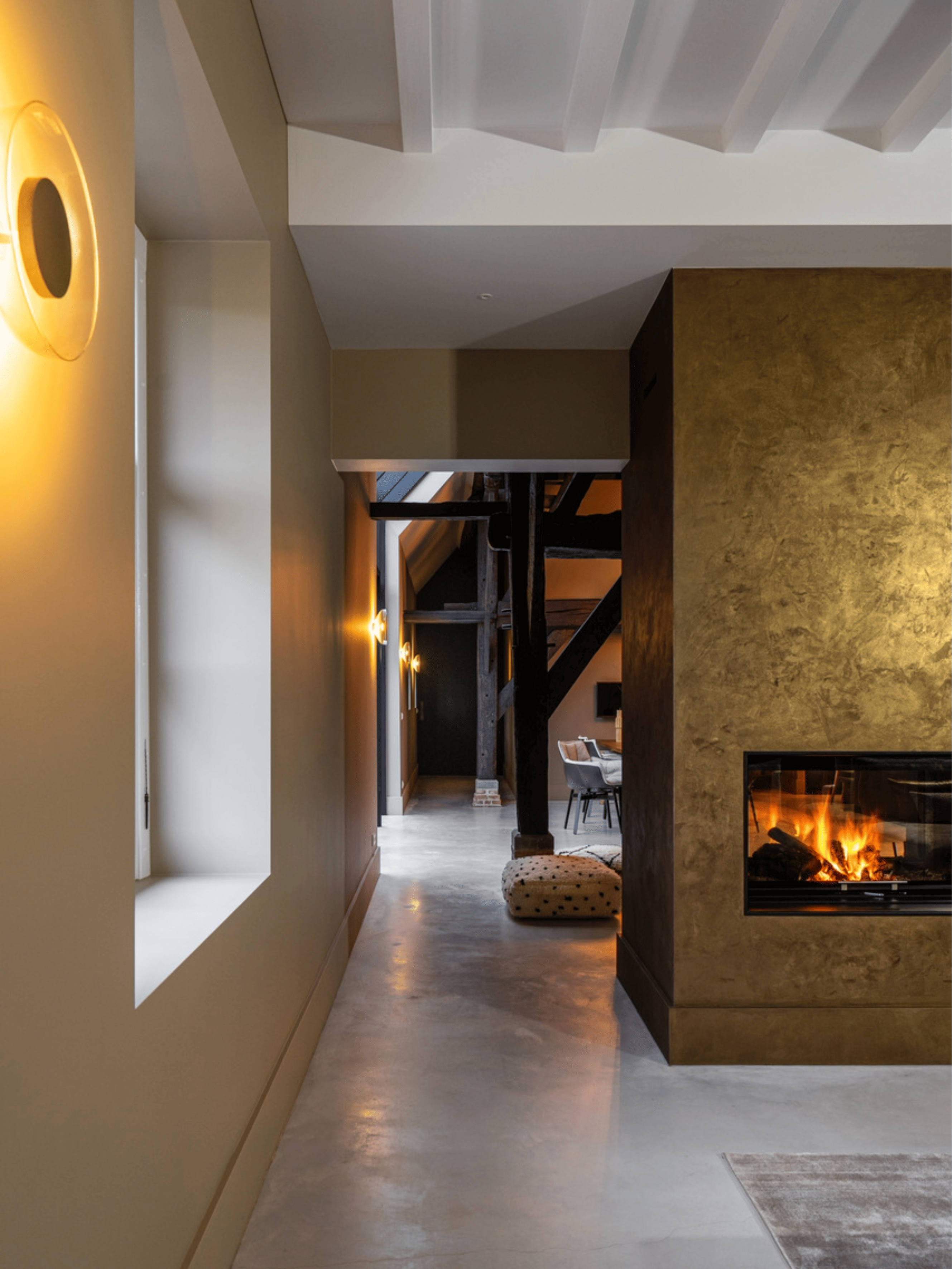 Moderne design open haard met hoogglans betonlook afwerking in fel goud. Luxe interieurwand met spiegelende structuur en elegante, exclusieve uitstraling in een eigentijdse leefruimte.