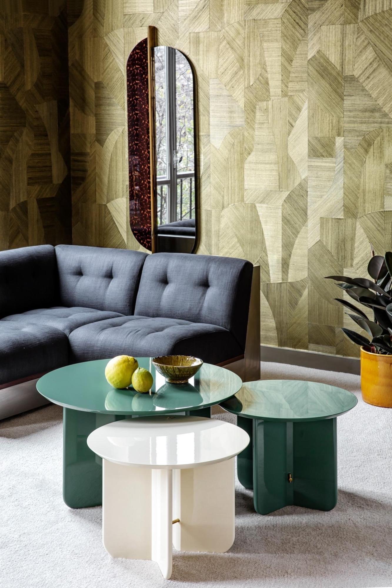 Showroom appartement RED met geometrisch groen geweven Arte Walls behang, blauwe zetel, donker roodbruin houten salontafel en planten. Modern interieur met warme materialen en natuurlijke accenten.