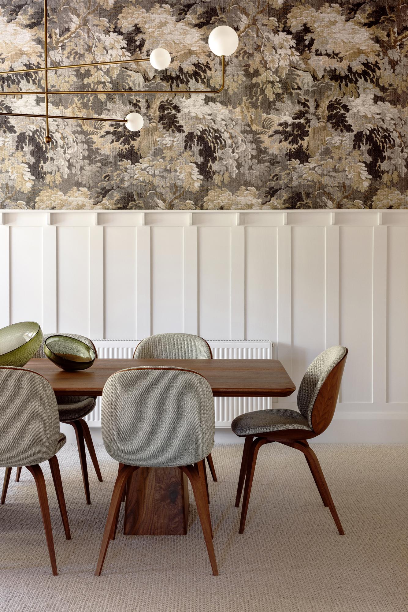 Eetkamer van Studio Esar met sierlijsten op de muren, hanglamp, witte muurverf en Arte Walls designbehang in natuurtinten. Houten tafel en stoelen gecombineerd met zachte stoffering voor een warme en stijlvolle sfeer.