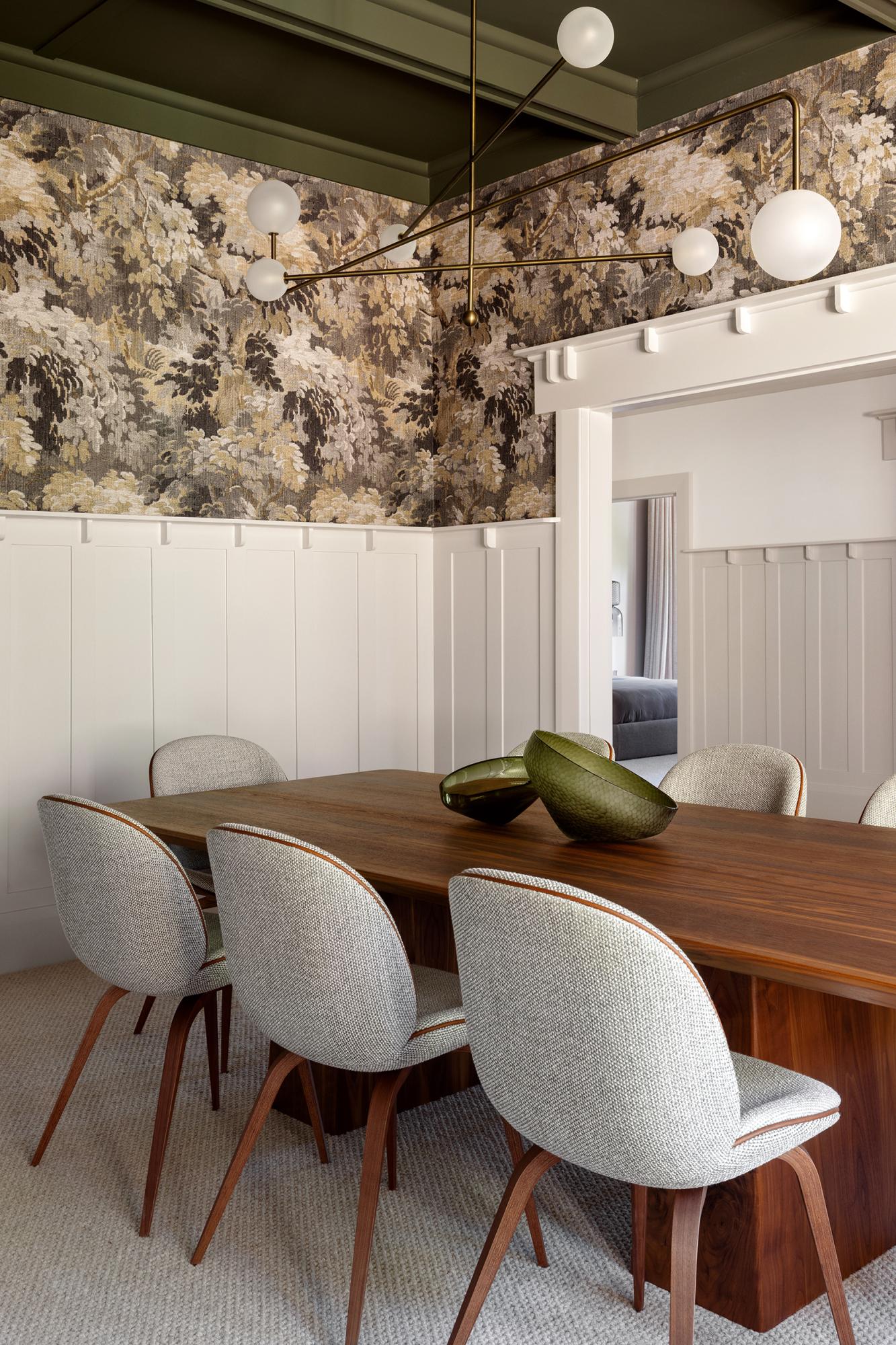 Eetkamer van Studio Esar met sierlijsten op de muren, hanglamp, witte muurverf en Arte Walls designbehang in natuurtinten. Houten tafel en stoelen gecombineerd met zachte stoffering voor een warme en stijlvolle sfeer.