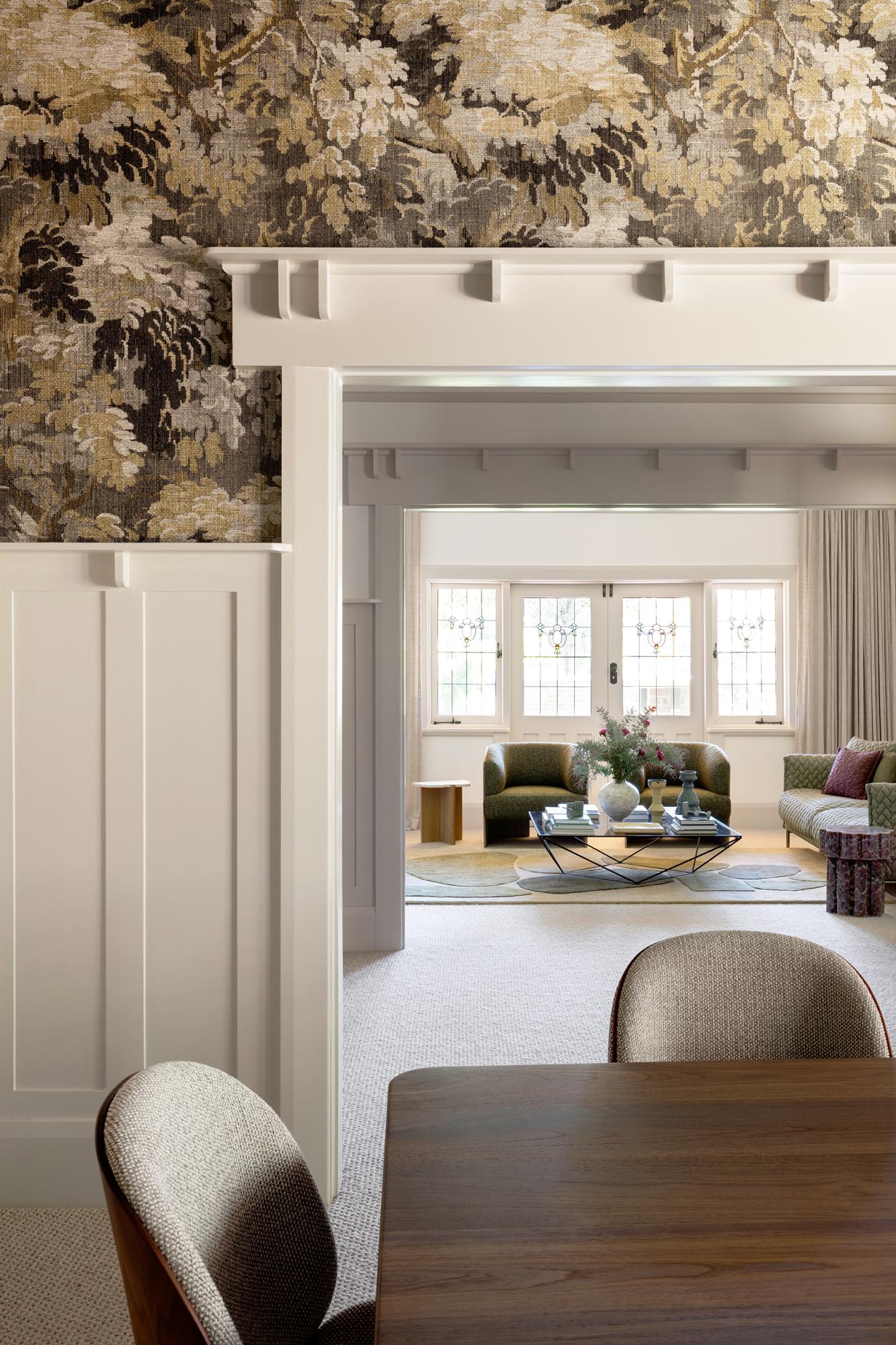 Eetkamer van Studio Esar met sierlijsten op de muren, hanglamp, witte muurverf en Arte Walls designbehang in natuurtinten. Houten tafel en stoelen gecombineerd met zachte stoffering voor een warme en stijlvolle sfeer.
