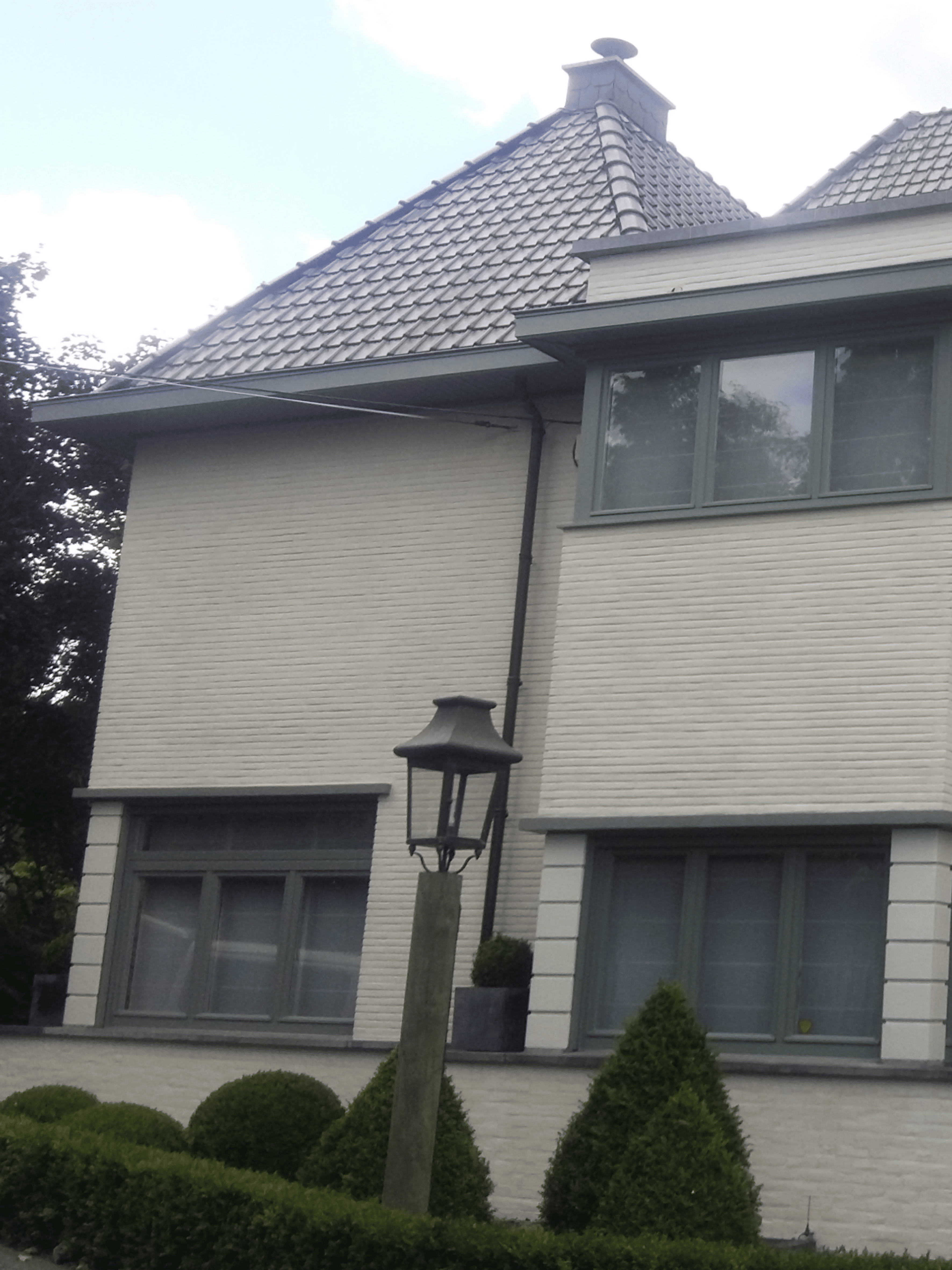 Landelijke woning met gekaleide gevel, groene voordeur en bronzen buitenverlichting