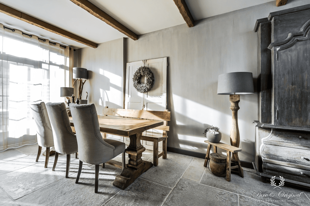 Gezellig landelijk interieur met decoratieve verftechnieken op de muren in zachte, warme tinten. Natuurlijke materialen, houten accenten en een authentieke, tijdloze sfeer met ambachtelijke wandafwerking.
