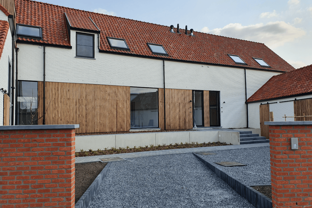 Moderne projectwoning met beige gekaleide gevel, houten gevelbekleding en oranje dakpannen. Duurzame gevelafwerking met een warme, landelijke uitstraling.