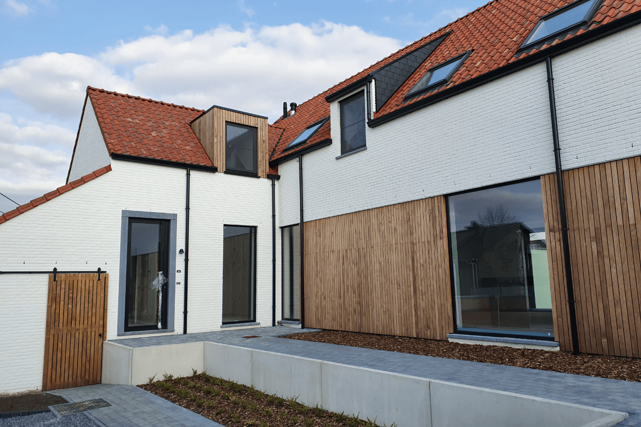 Moderne projectwoning met beige gekaleide gevel, houten gevelbekleding en oranje dakpannen. Duurzame gevelafwerking met een warme, landelijke uitstraling.