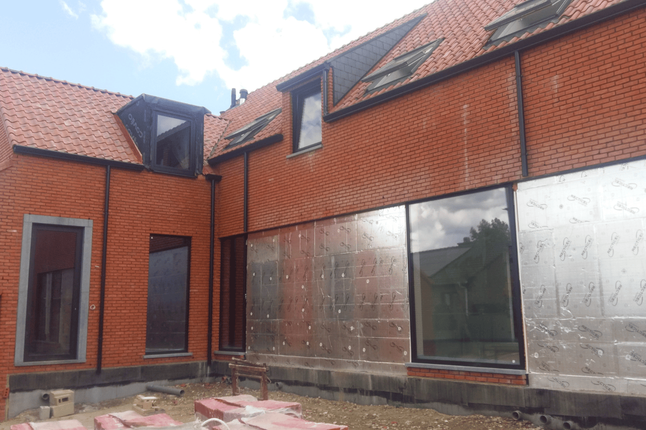 Moderne projectwoning met beige gekaleide gevel, houten gevelbekleding en oranje dakpannen. Duurzame gevelafwerking met een warme, landelijke uitstraling.