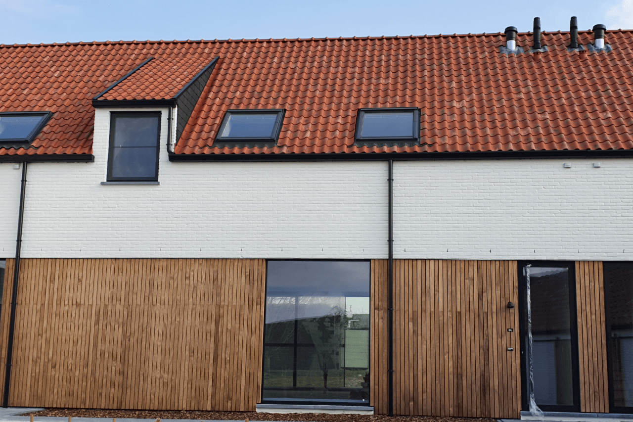 Moderne projectwoning met beige gekaleide gevel, houten gevelbekleding en oranje dakpannen. Duurzame gevelafwerking met een warme, landelijke uitstraling.