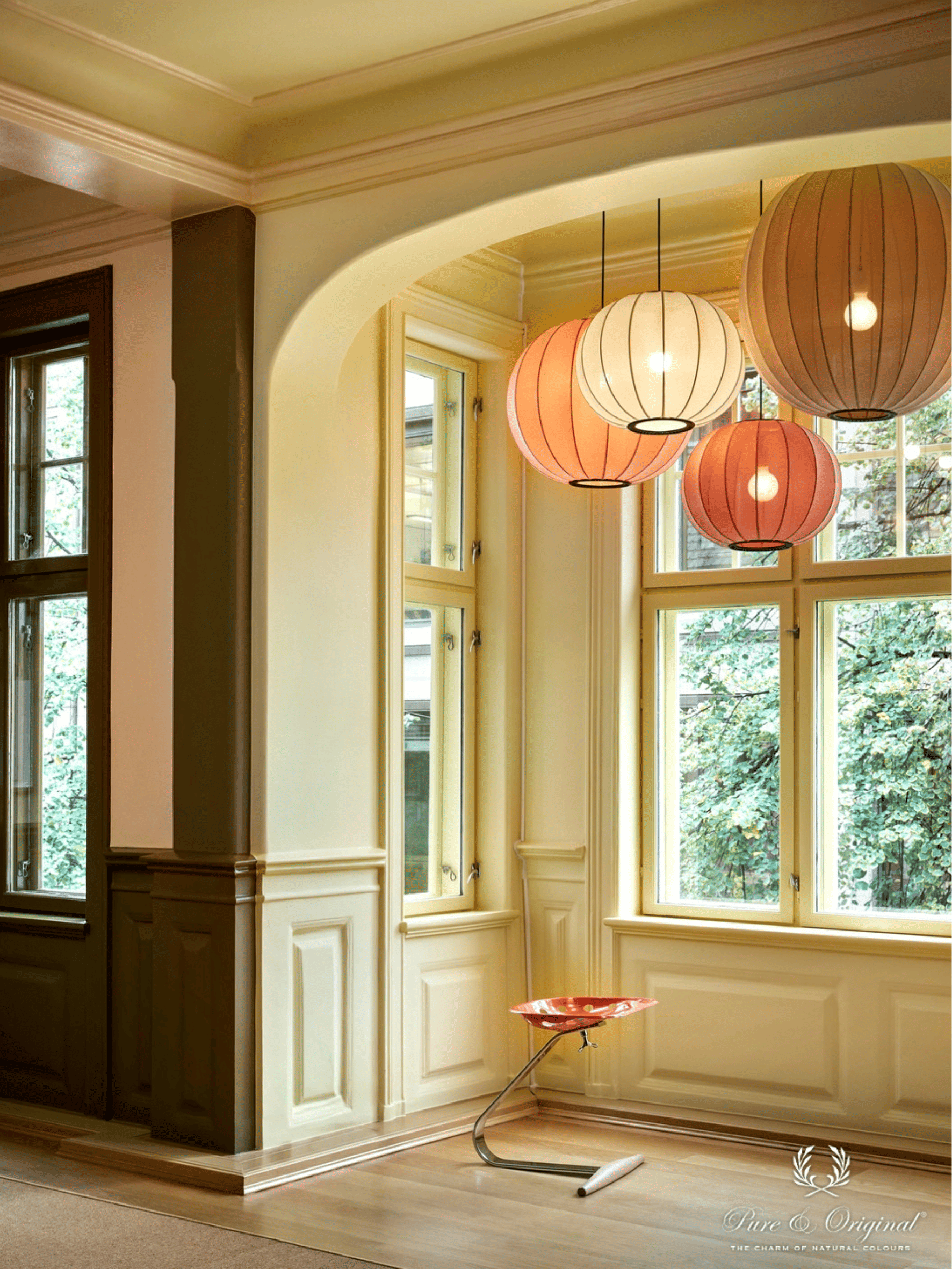 Interieur met geelgroene verf op muren en plafond, gecombineerd met een donkergroene accentmuur. Warme oranje decoratieve accenten en een houten vloer zorgen voor een levendig en stijlvol interieur met natuurlijke kleuren.