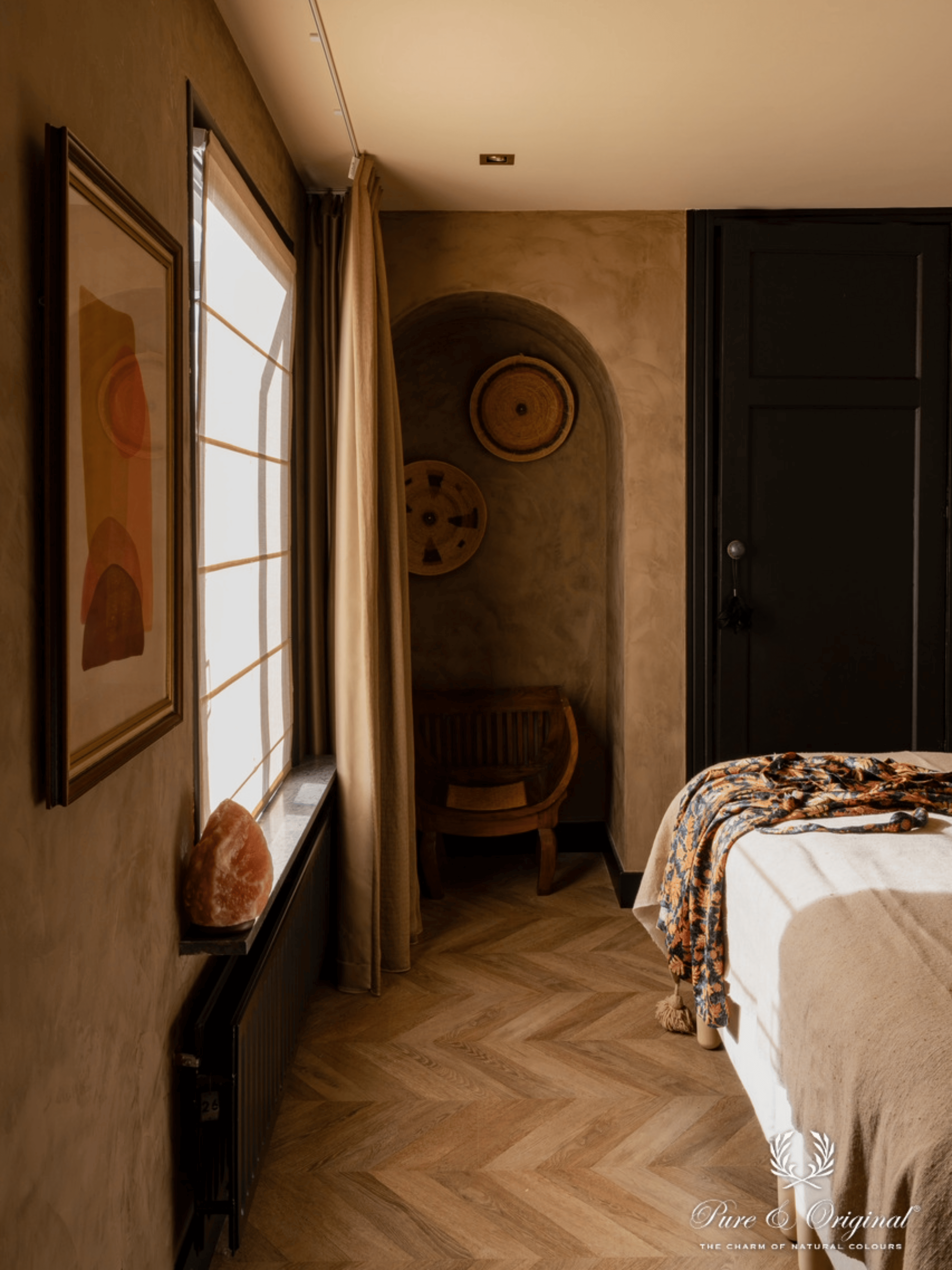 Interieur met een warme bruine decoratieve verftechniek op de muren, gecombineerd met Afrikaanse interieuraccenten en souvenirs uit wereldlanden. Sfeervolle slaapkamer en badkamer met natuurlijke materialen en een exotische, persoonlijke uitstraling.