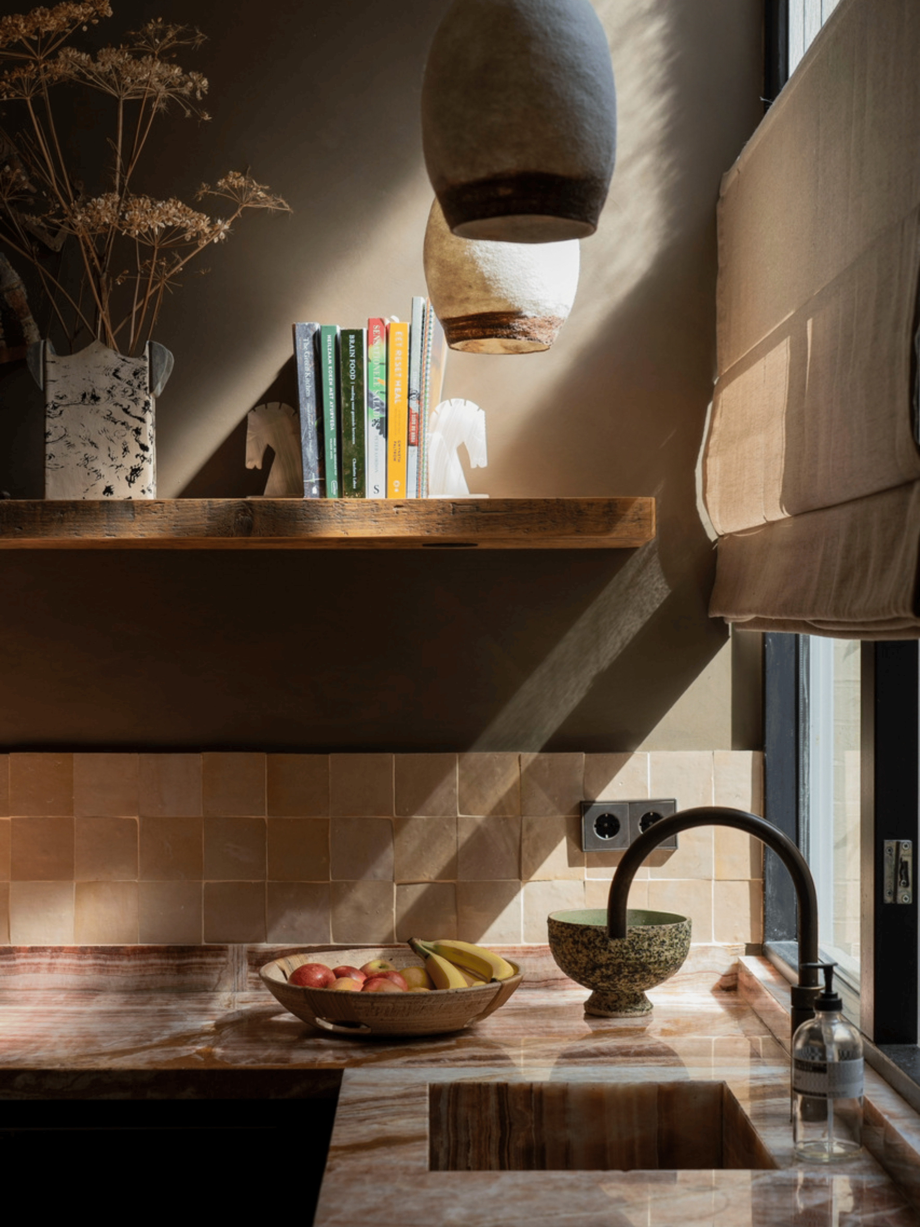 Landelijke eetkamer met bordeauxkleurige keukenkasten, zacht beige-groene wandafwerking en een houten eettafel. Witte rozen als decoratie zorgen voor een frisse en elegante, warme sfeer in het interieur.