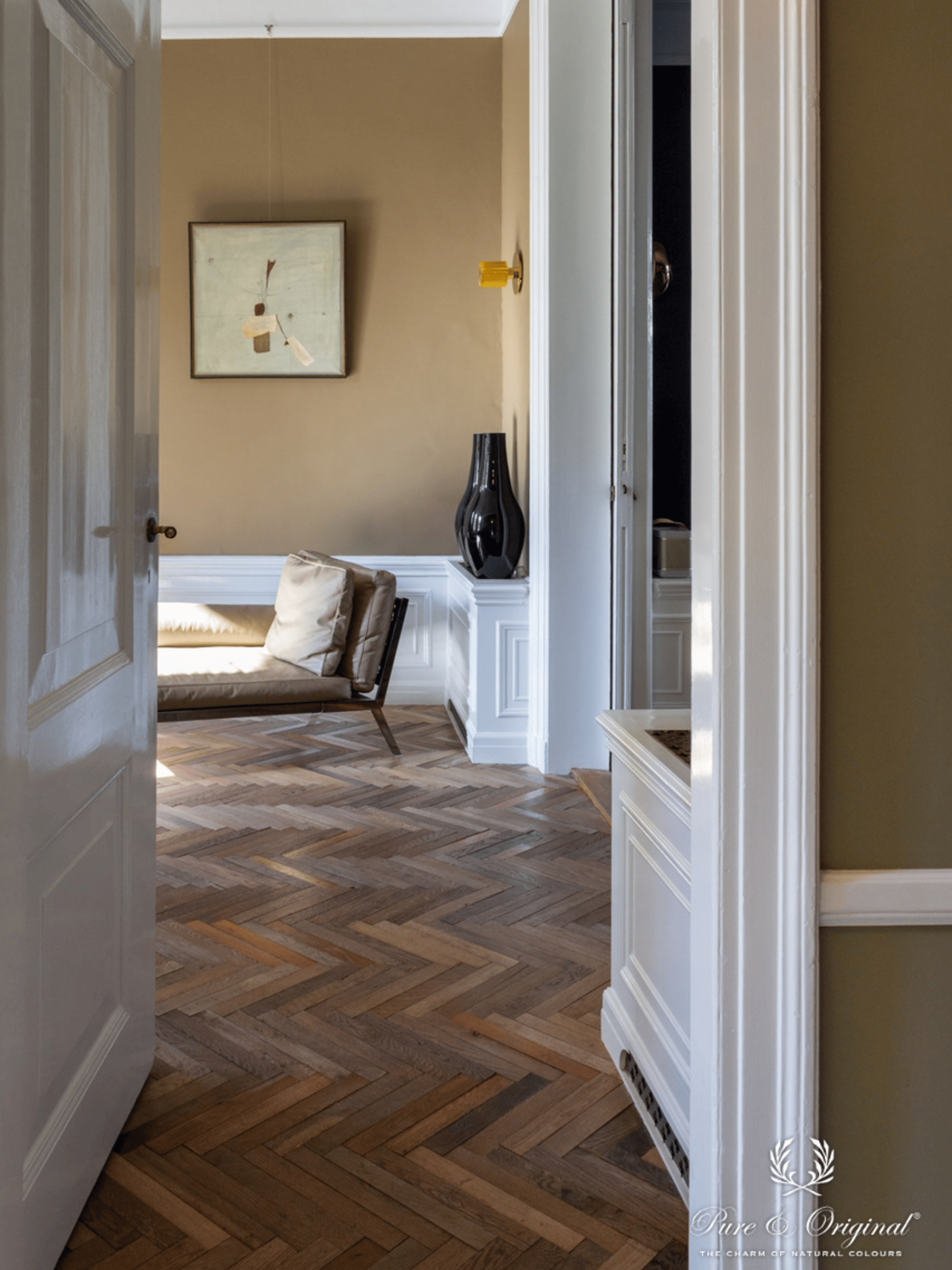 Een beige kleur met een geel/groene ondertoon op de muren gecombineerd met prachtige wandlijsten in het wit waardoor de wandlijsten nog mooier tot zijn recht komen. Een visgraat vloer in donker bruin hout materiaal