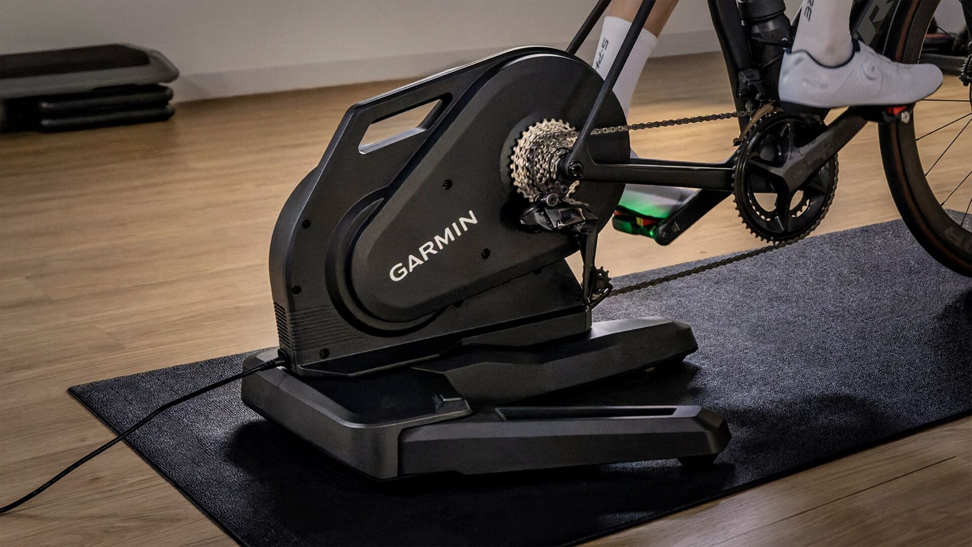 Home trainer Garmin Tacx Nēra avec un vélo de route sur un tapis Tacx